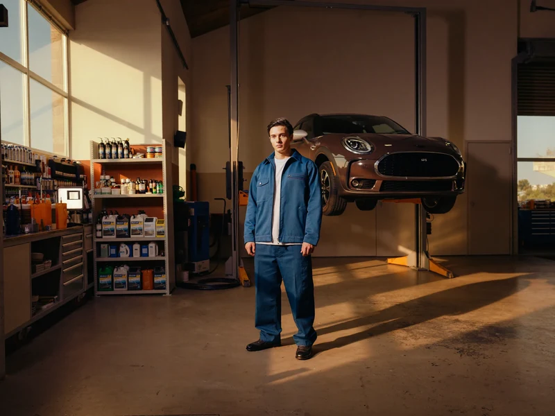 Helle Auto-Service-Werkstatt mit Hatchback auf der Hebebühne und Pflegeprodukten im Regal